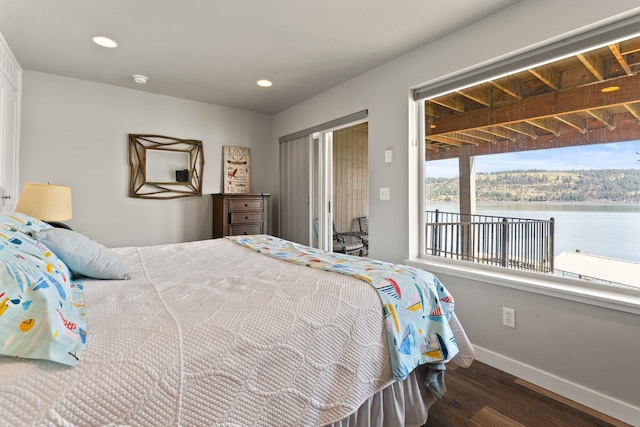 bedroom featuring dark wood-type flooring and a water view