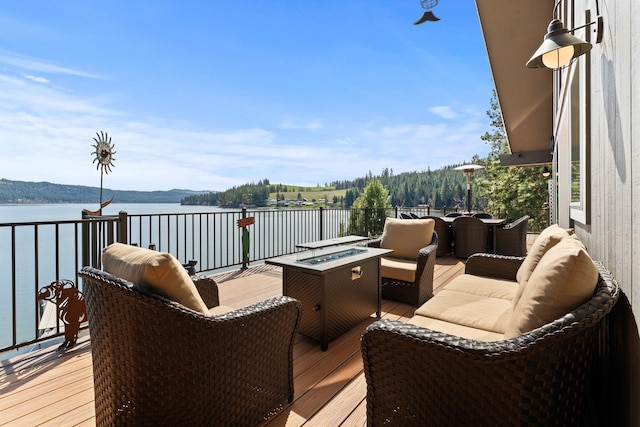 wooden deck featuring a water view and an outdoor living space with a fire pit