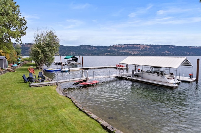 view of dock with a water view and a lawn