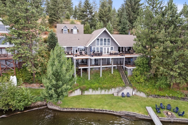 rear view of property with a yard, a fire pit, and a deck with water view