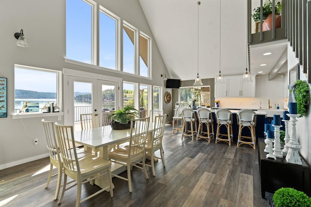 dining area featuring a towering ceiling, a wealth of natural light, dark hardwood / wood-style flooring, and french doors