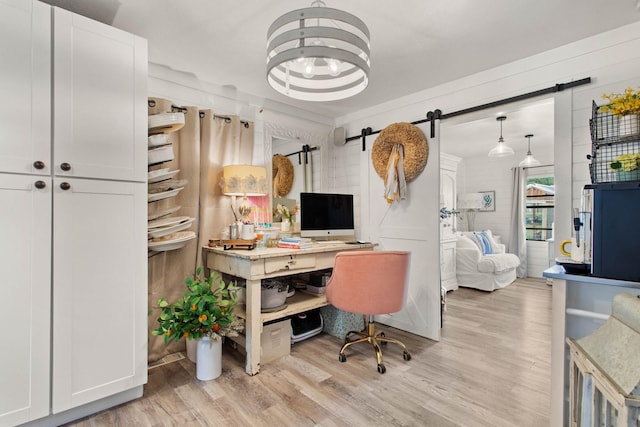 office area featuring a barn door, an inviting chandelier, and light hardwood / wood-style flooring