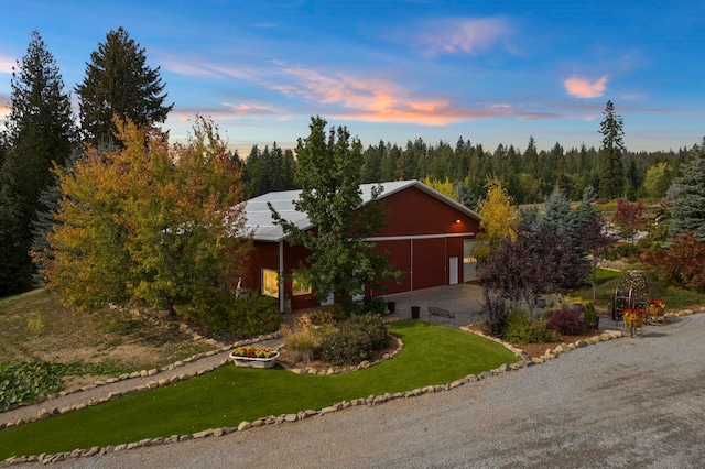 view of front of home featuring a garage, a yard, and an outbuilding