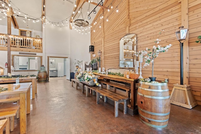 interior space featuring concrete flooring, a towering ceiling, and wooden walls