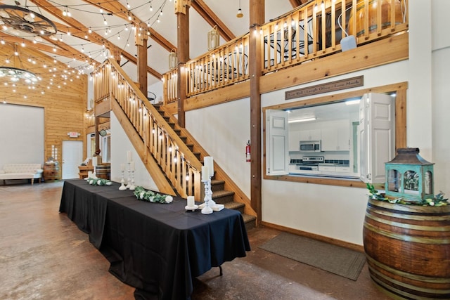 stairs featuring wood walls, a high ceiling, and concrete flooring