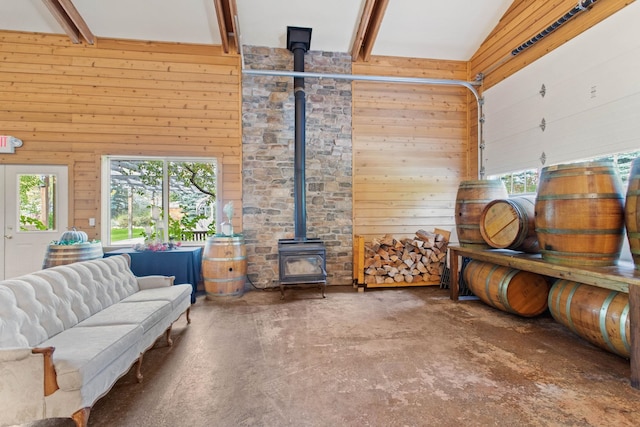 living room featuring concrete floors, a wood stove, a high ceiling, and wood walls