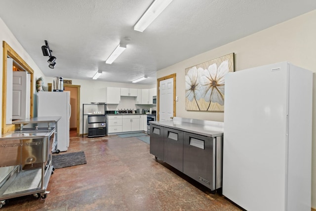 kitchen with white cabinets, white refrigerator, a textured ceiling, and range