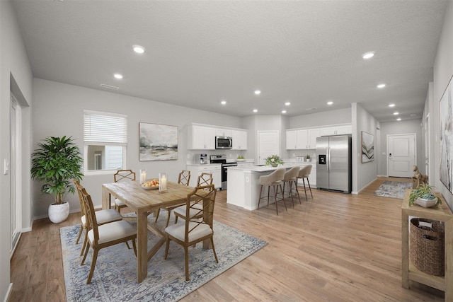 dining space featuring light wood-type flooring and a textured ceiling