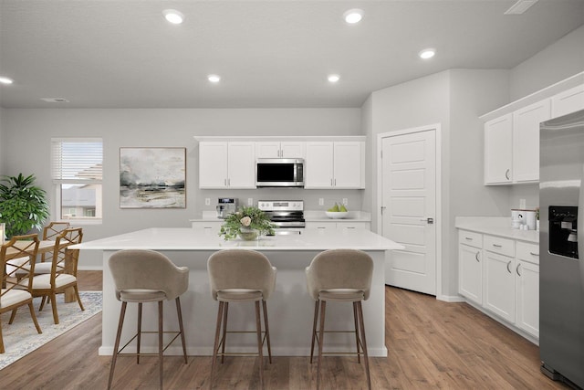 kitchen with appliances with stainless steel finishes, white cabinetry, and a kitchen island