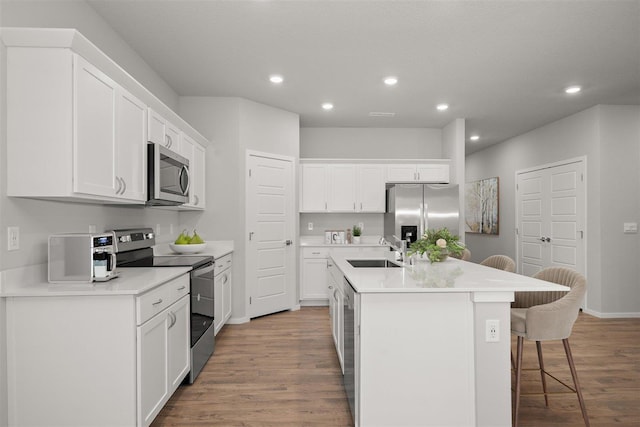 kitchen featuring white cabinetry, a center island with sink, a breakfast bar area, appliances with stainless steel finishes, and sink