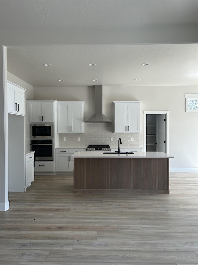 6010 N Windsor St, Spokane, WA 99208 - kitchen with wall chimney range hood, light wood-type flooring, a sink, stainless steel appliances, and white cabinetry