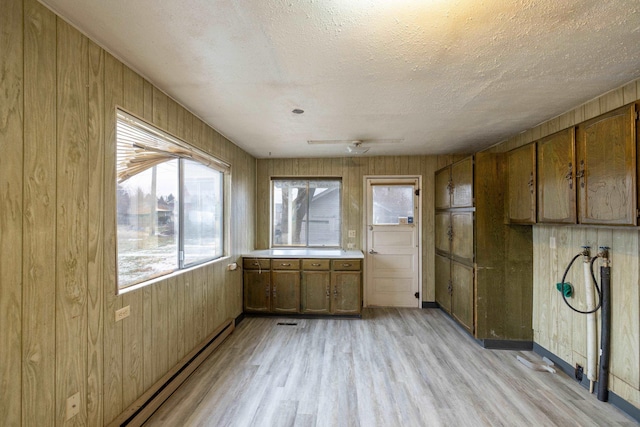 kitchen featuring a textured ceiling, wood walls, and light wood-type flooring