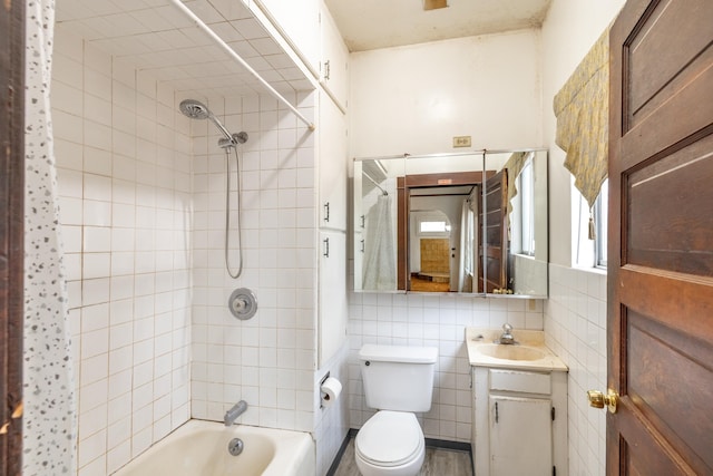 full bathroom featuring toilet, vanity, tile walls, and tiled shower / bath