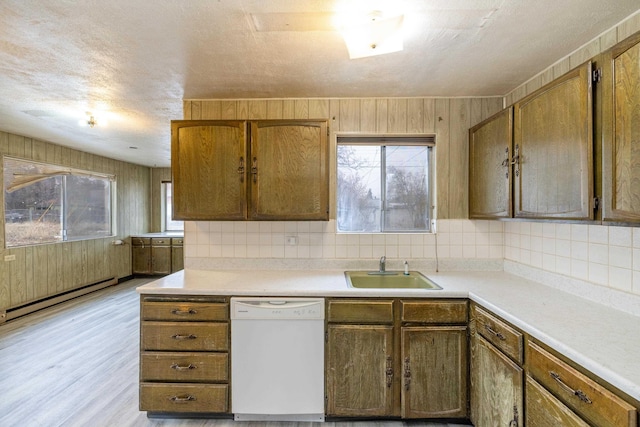 kitchen featuring white dishwasher, sink, decorative backsplash, and a baseboard heating unit