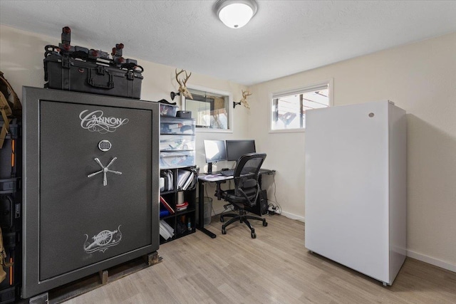 home office with light wood-type flooring and a textured ceiling