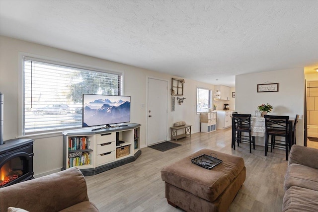 living room featuring light hardwood / wood-style floors, a wood stove, and a textured ceiling