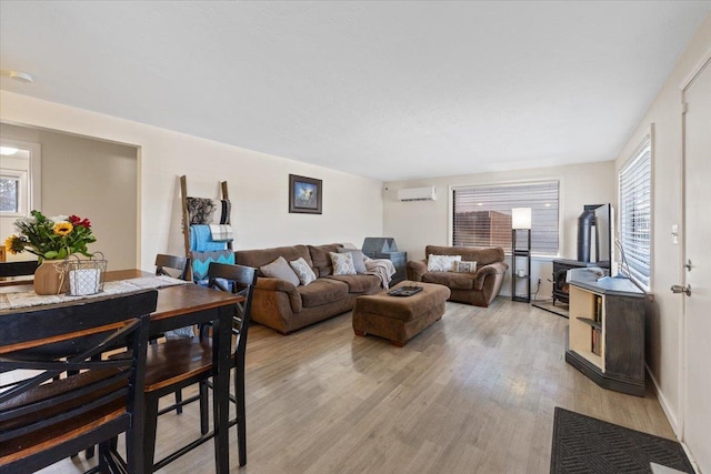 living room with plenty of natural light, light hardwood / wood-style floors, and an AC wall unit