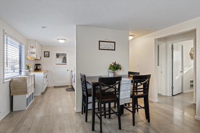 dining room with light hardwood / wood-style floors and a textured ceiling