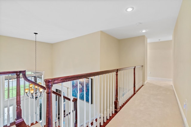 hallway featuring carpet floors and a chandelier