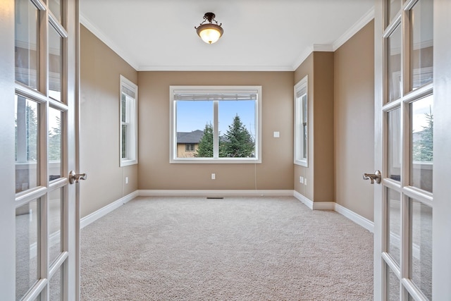 carpeted spare room with plenty of natural light, ornamental molding, and french doors