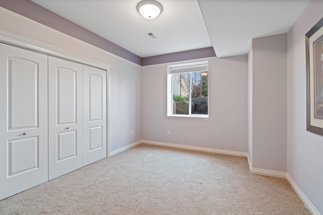 unfurnished bedroom with light colored carpet and a closet