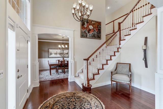 foyer entrance featuring a high ceiling, a chandelier, ornamental molding, and dark hardwood / wood-style flooring