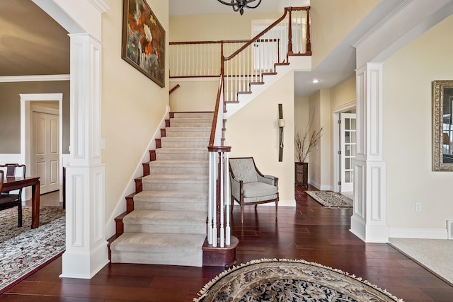 interior space featuring wood-type flooring, crown molding, and decorative columns