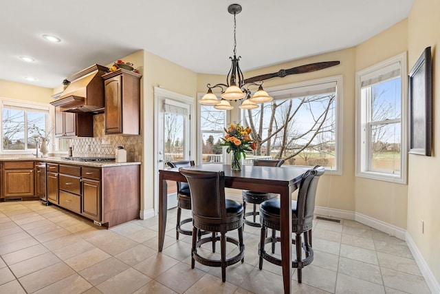 dining space featuring a wealth of natural light, light tile patterned floors, and an inviting chandelier