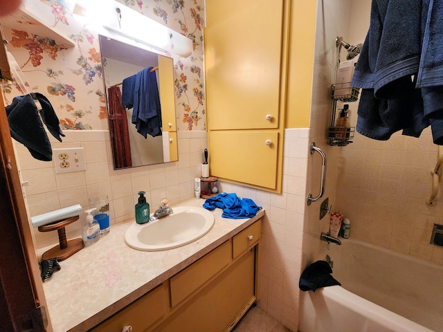 bathroom featuring tile walls, tiled shower / bath, and vanity