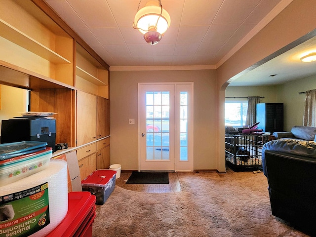 entryway with crown molding and carpet flooring