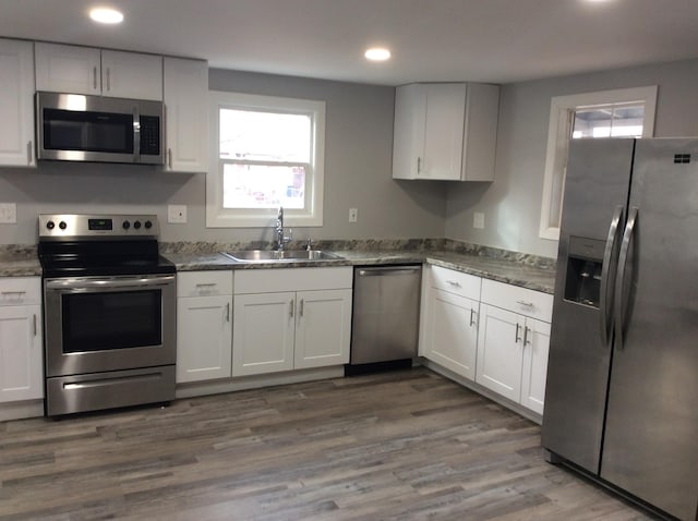 kitchen with white cabinets, wood-type flooring, appliances with stainless steel finishes, and sink