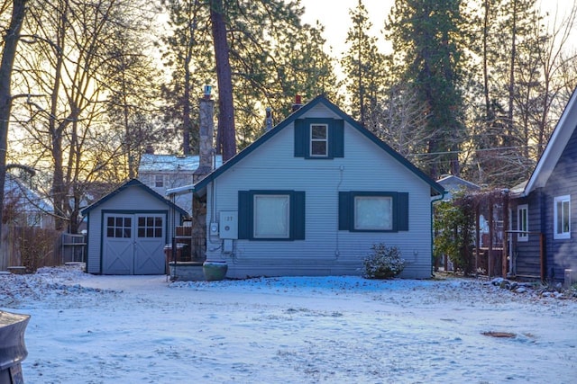 snow covered house featuring an outdoor structure and a garage