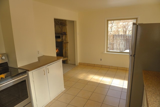 kitchen featuring light tile patterned floors, appliances with stainless steel finishes, and white cabinets