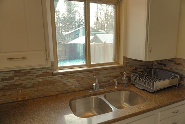 kitchen featuring white cabinetry, backsplash, dark stone counters, and sink