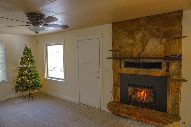 unfurnished living room with ceiling fan, a stone fireplace, and carpet flooring