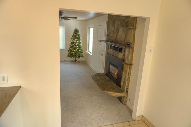 carpeted living room with ceiling fan and a fireplace