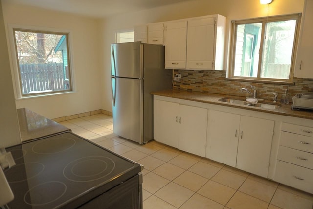 kitchen with tasteful backsplash, stainless steel refrigerator, black range with electric cooktop, white cabinets, and sink