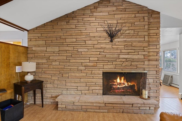 interior space featuring light wood-type flooring, a baseboard heating unit, a fireplace, and lofted ceiling