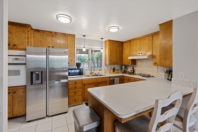 kitchen featuring sink, decorative light fixtures, kitchen peninsula, stainless steel appliances, and light tile patterned flooring