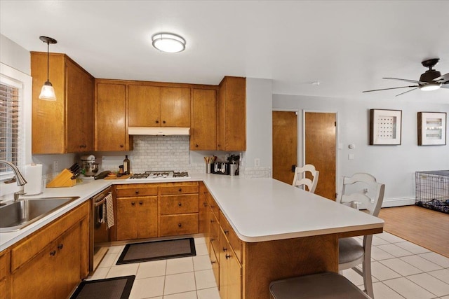 kitchen featuring dishwasher, sink, hanging light fixtures, kitchen peninsula, and light tile patterned floors