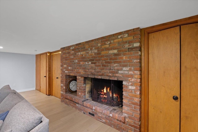 living room with a brick fireplace and light hardwood / wood-style floors