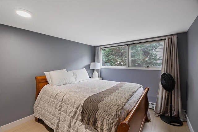 bedroom with a baseboard radiator and light hardwood / wood-style flooring