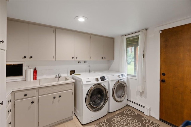 washroom with sink, cabinets, a baseboard heating unit, and washing machine and clothes dryer