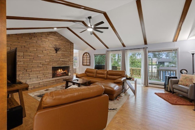 living room featuring ceiling fan, light hardwood / wood-style floors, vaulted ceiling with beams, and a stone fireplace