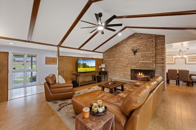 living room with a stone fireplace, high vaulted ceiling, light hardwood / wood-style flooring, beam ceiling, and ceiling fan with notable chandelier