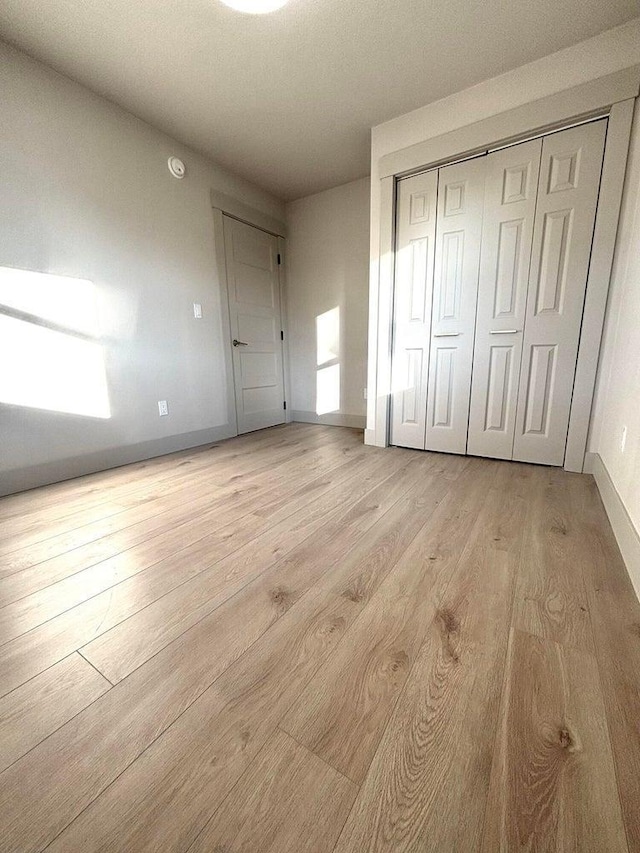 unfurnished bedroom with light hardwood / wood-style flooring and a closet