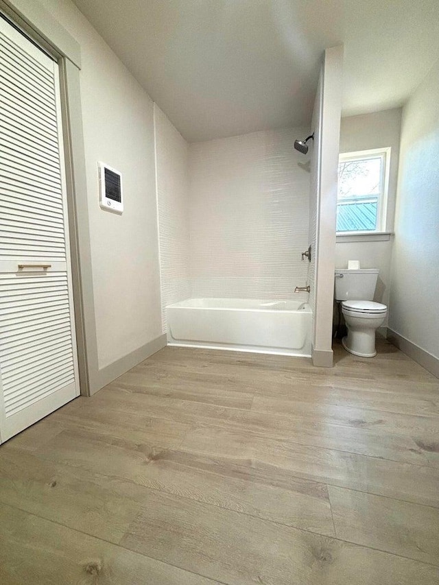 bathroom with toilet, tiled shower / bath, and wood-type flooring