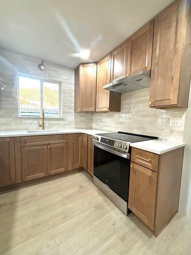 kitchen with sink, light wood-type flooring, electric range, and tasteful backsplash