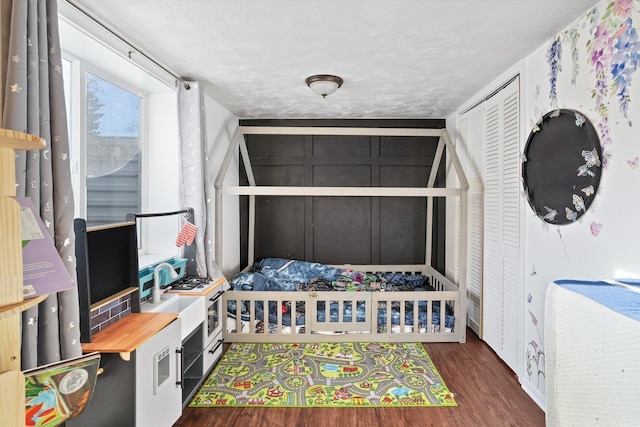 bedroom with dark hardwood / wood-style floors, a textured ceiling, and a closet