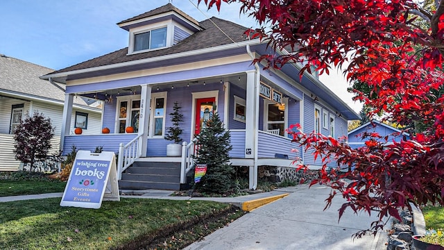 bungalow-style home with covered porch and a front yard